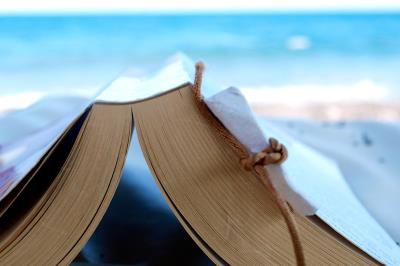 Libro aperto, capovolto, su una spiaggia.